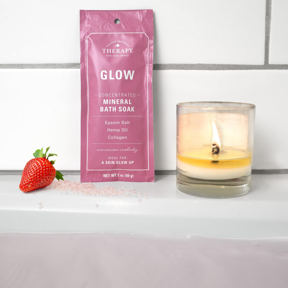 Village Naturals Therapy Glow container with steam conveys a warm, inviting bath experience